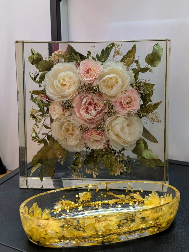 Blumenarrangement in Harz, umgeben von einer goldenen Schale mit Mischfarbe.