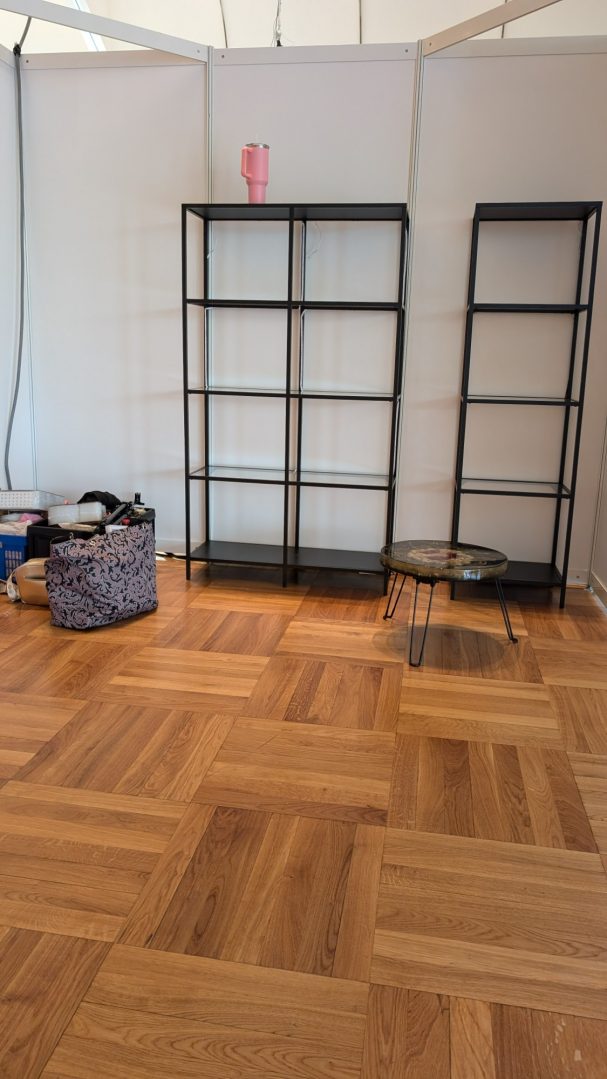 Leere Regale aus schwarzem Metall, Holzfußboden, ein paar Taschen am Boden.