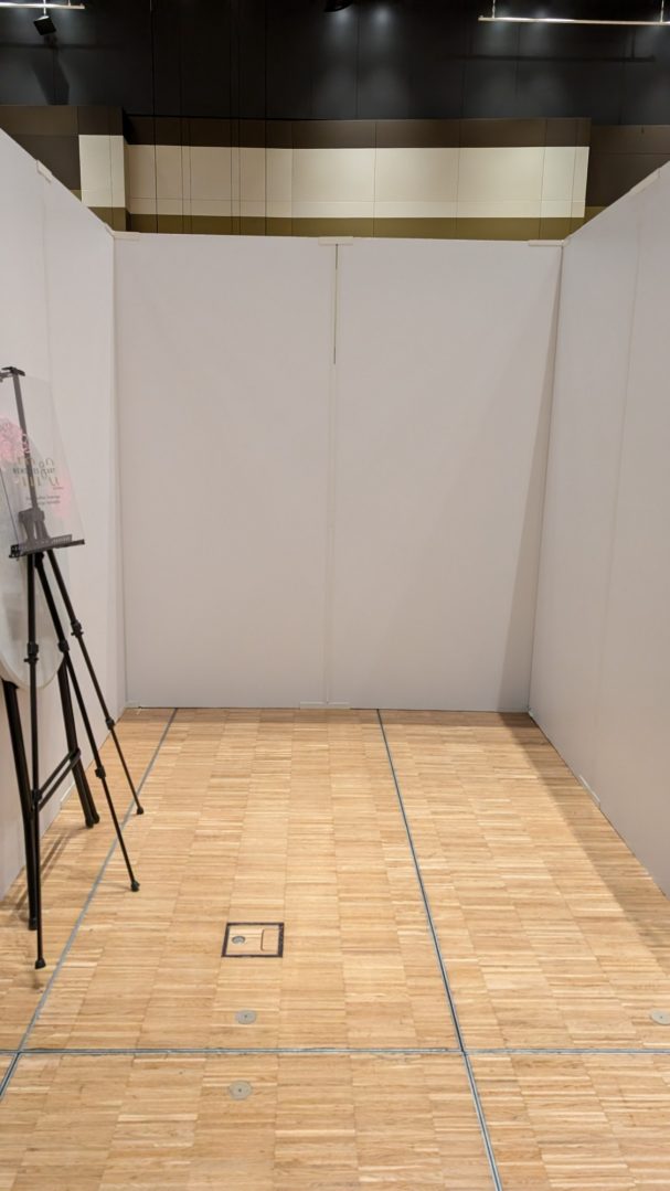 Leerer Raum mit Holzboden und einer Staffelei in einer Ecke.