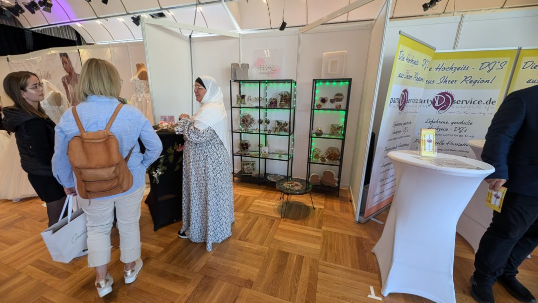 Messestand mit Besuchern, in einem Raum mit Ständen und Informanten.