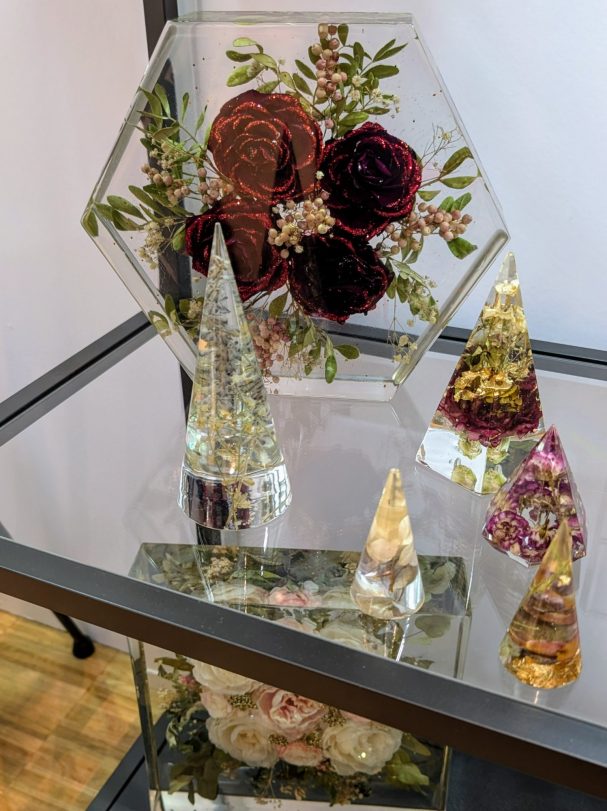 Dekorative, gläserne Objekte mit Trockenblumen und Pflanzen in verschiedenen Formen.
