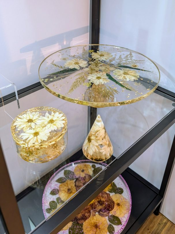 Glasvitrine mit dekorativen, blumenmuster-verzierten Objekten in verschiedenen Formen.