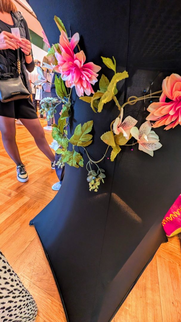 Schwarzer Stoff mit bunten Blumen und grünem Blattwerk dekoriert.