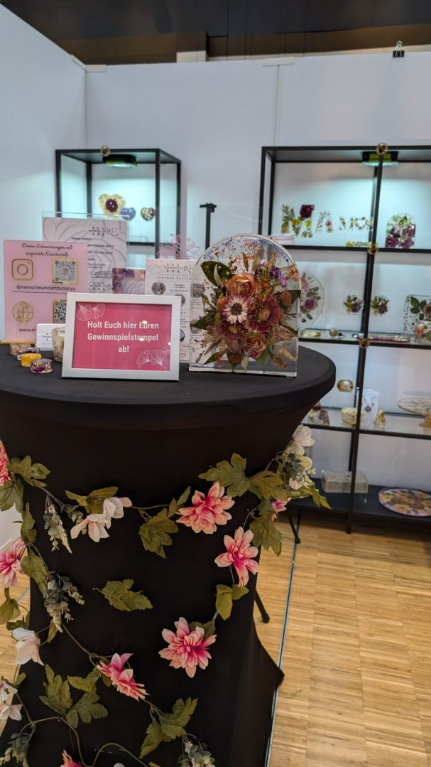 Blumenarrangement auf einem Tisch, umgeben von dekorativen Objekten in einer Ausstellung.