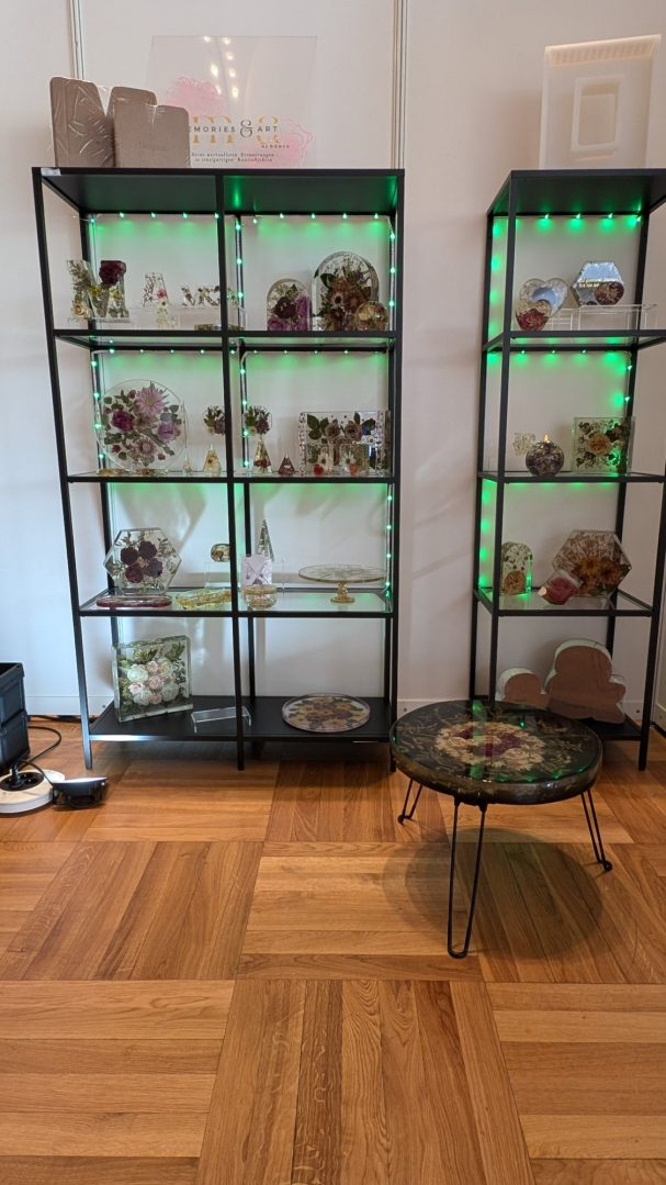 Vitrine mit dekorativen Objekten und Pflanzen, beleuchtet mit grünem Licht.