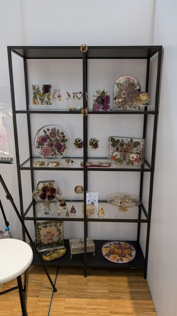 Regal aus schwarzem Metall mit getrockneten Blumen und Kunsthandwerk in mehreren Fächern.